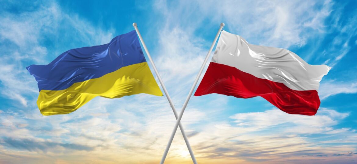 crossed national flags of Ukraine and poland flag waving in wind