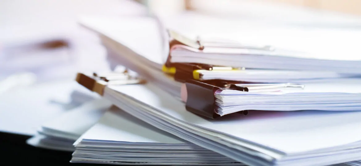 Stack of papers documents in archives files with clip papers on table at offices,  Busy offices and Pile of data unfinished folders on office desk indoor near window,  Business concept.